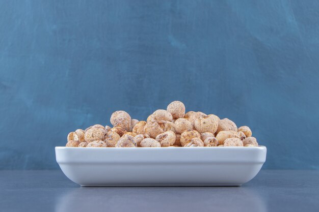 Copos de maíz dulces con muesli en un bol, sobre el fondo de mármol.