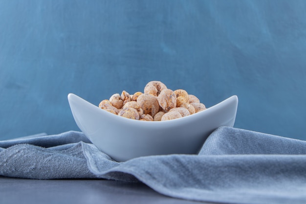 Copos de maíz con muesli en un cuenco sobre un trozo de tela, sobre el fondo de mármol. Foto de alta calidad