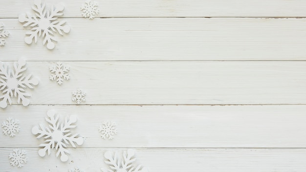 Copos de nieve decorativos de Navidad laicos planos sobre tabla de madera