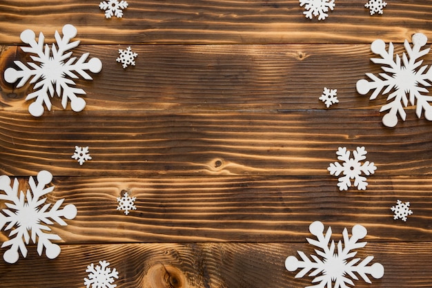 Copos de nieve de invierno lindo endecha plana sobre fondo de madera