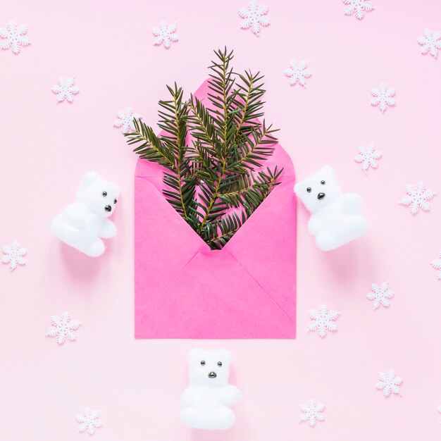 Copos de nieve y osos alrededor de sobre con ramas de coníferas