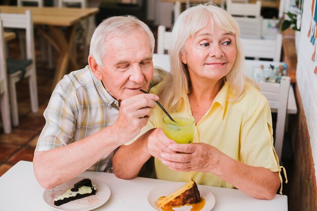 Coquetear pareja senior en café disfrutando de una bebida