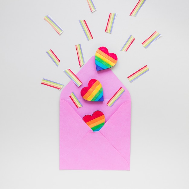 Corazón de arco iris con arco iris de papel esparcidos de un sobre
