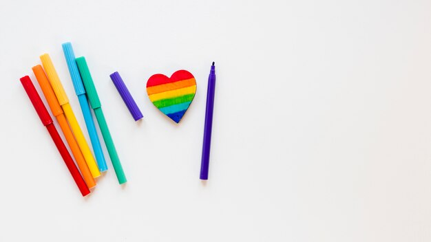 Corazón de arcoiris con rotuladores en mesa blanca