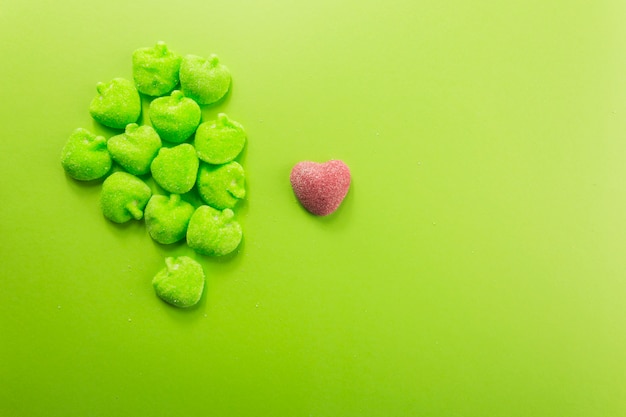 Foto gratuita corazón de caramelo cerca de montón de manzanas de gelatina