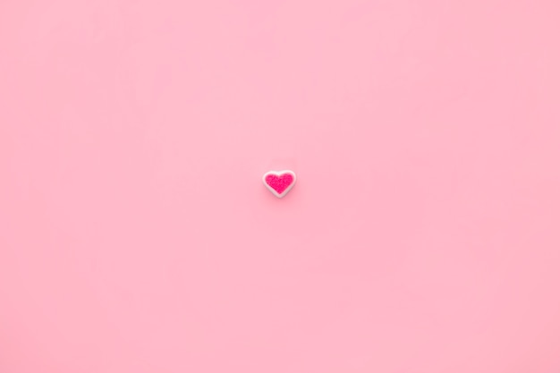 Corazón de caramelo solitario sobre fondo rosa