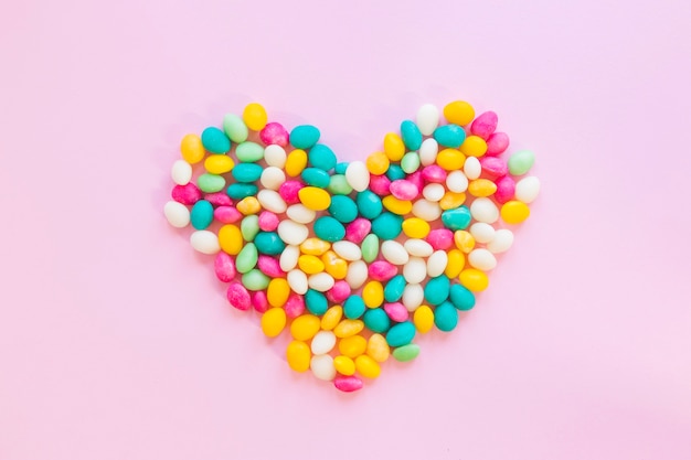 Corazón colorido del caramelo en la tabla rosada