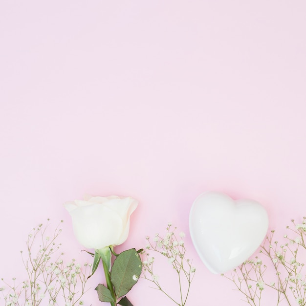Foto gratuita corazón decorativo blanco cerca de plantas y rosa.