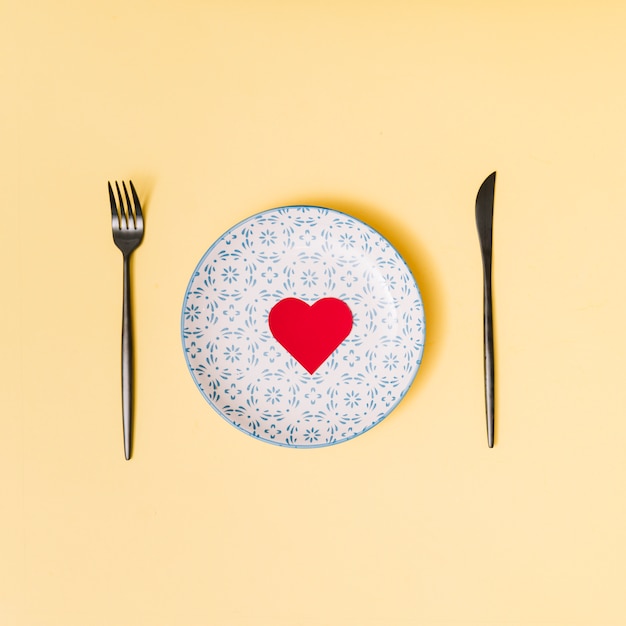 Foto gratuita corazón decorativo en plato hermoso entre cubiertos.