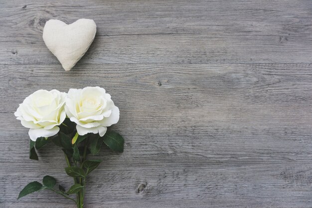 Corazón y flores blancas sobre superficie de madera