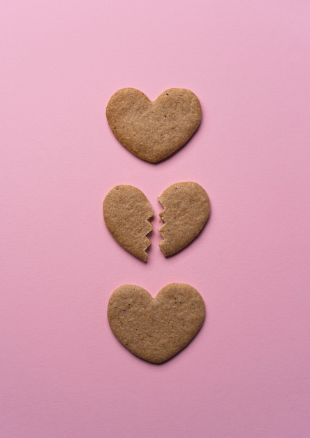 Corazón de galleta rota endecha plana sobre fondo rosa