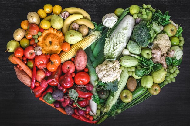 Corazón hecho de frutas y verduras frescas sobre fondo de madera