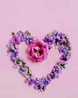 Foto gratuita corazón hecho con lavanda y flor rosada en fondo rosado