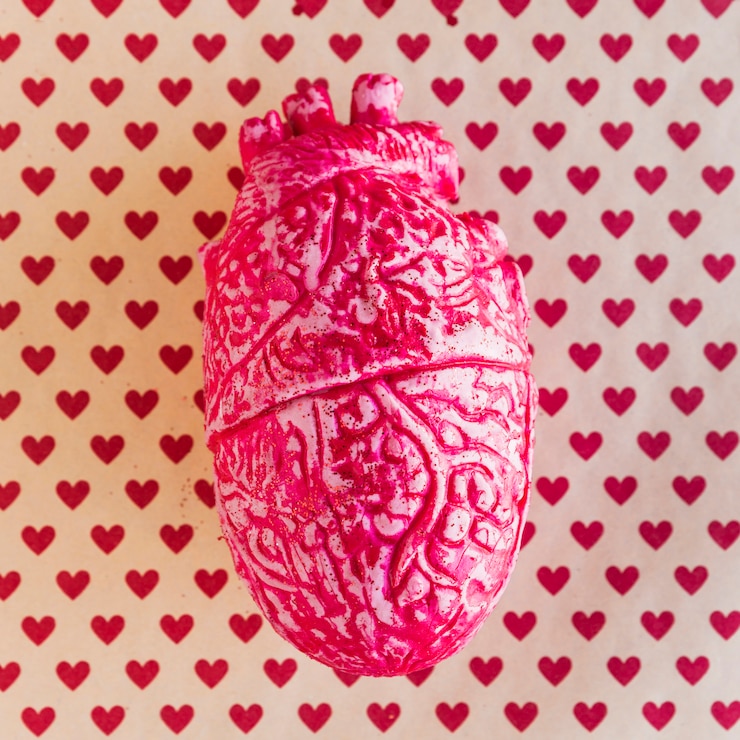 Foto gratuito corazón humano de cerámica roja en mesa con patrón de corazón