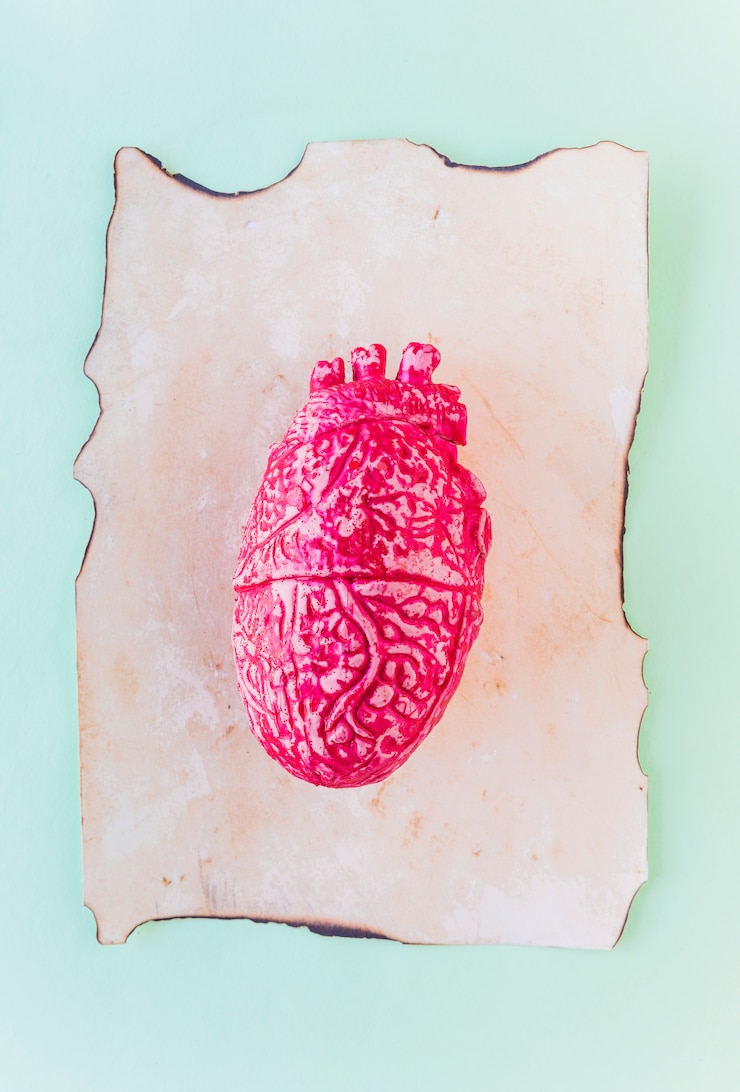 Foto gratuito corazón humano de cerámica rosa sobre papel viejo