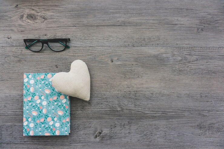 Foto gratuito corazón, libro y gafas sobre superficie de madera