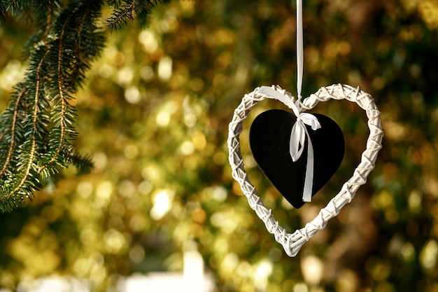 Foto gratuita corazón negro puesto en el corazón blanco cuelgue del árbol