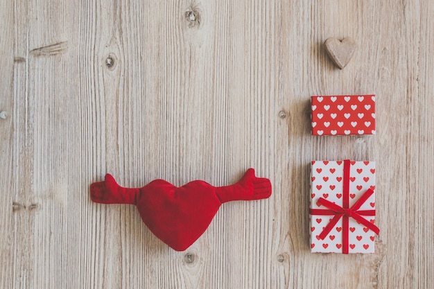 Corazón de peluche con brazos y manos y cajas de regalo