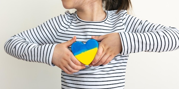 Corazón pintado con los colores de la bandera de ucrania en manos de niños