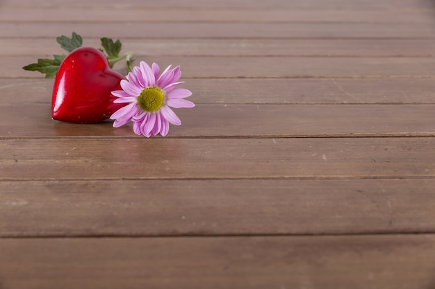 Corazón rojo y flor en una mesa