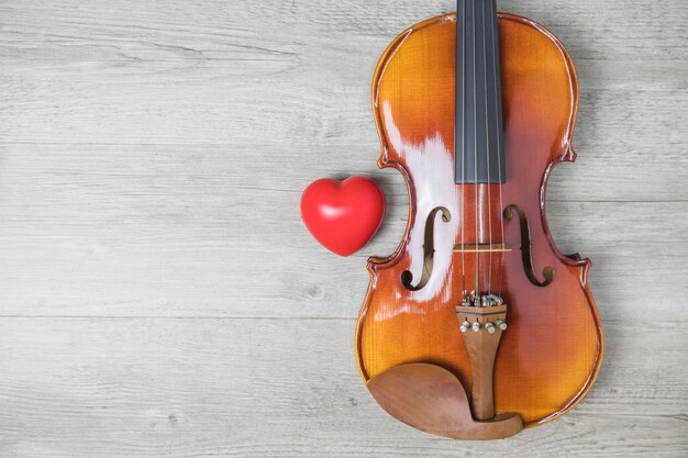 Corazón rojo y guitarra clásica de madera en la mesa gris