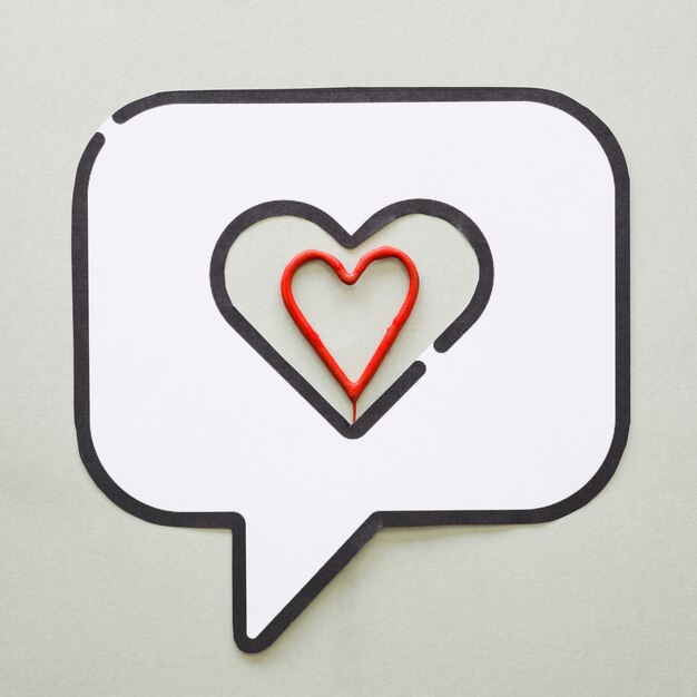 Corazón rojo en el icono de discurso de burbuja en la mesa