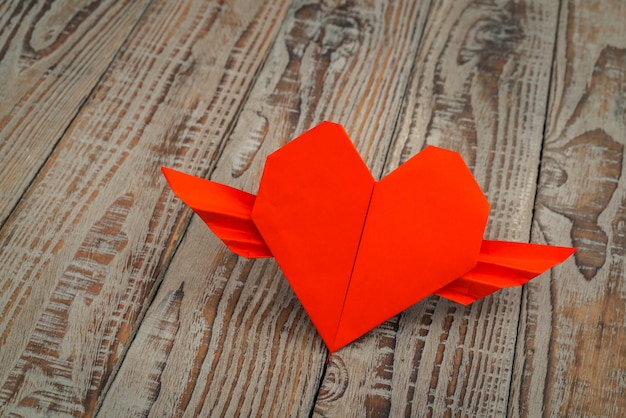 Foto gratuita corazón rojo del origami de papel con las alas en el fondo de madera.