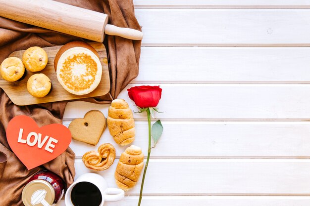 Corazón y rosa cerca de pasteles en blanco