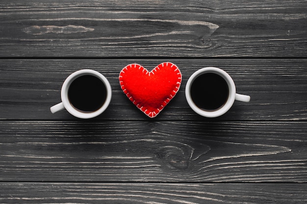 Corazón entre taza de café sobre fondo gris