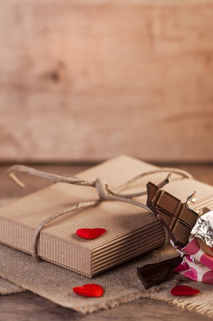 Corazones, chocolate y regalo de San Valentín sobre fondo de madera