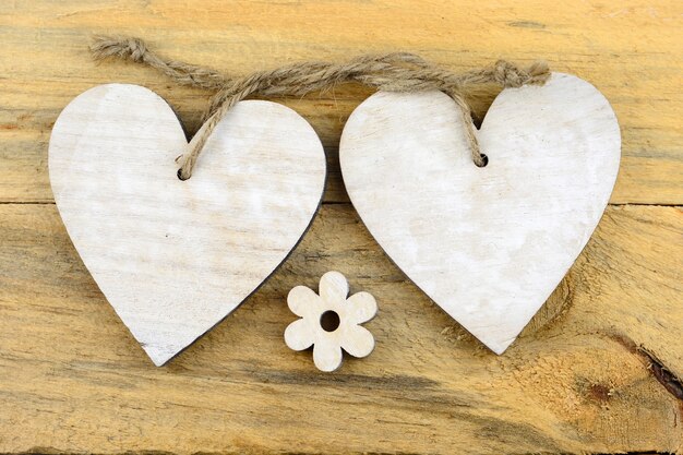 Corazones de madera blanca y una flor sobre una superficie de madera