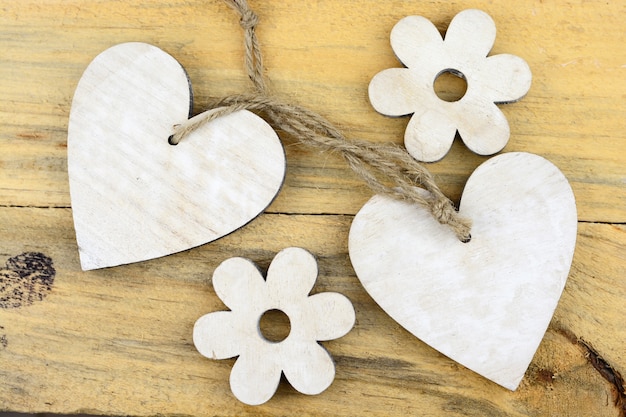 Corazones de madera blanca y flores sobre una superficie de madera