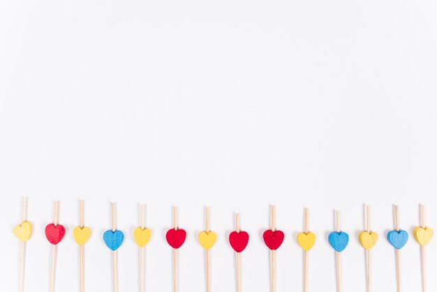 Corazones de madera pequeños en palos en mesa blanca