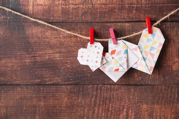 Corazones de papel con alfileres enganchados en hilo.