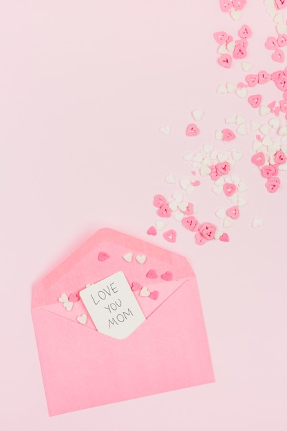 Corazones de papel decorativo cerca de sobre con etiqueta con palabras