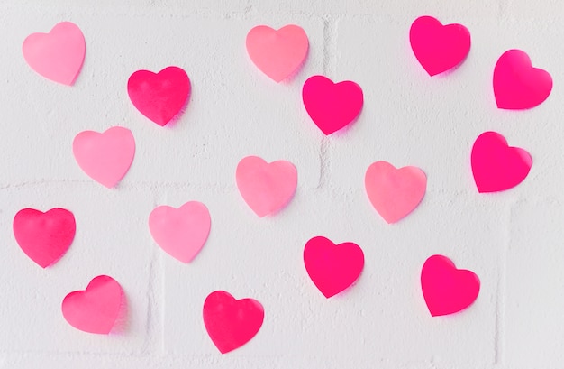 Corazones de papel pequeños en pared blanca