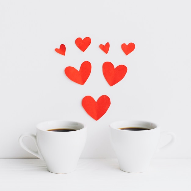 Foto gratuita corazones de papel entre tazas de café