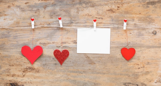 Foto gratuita corazones rojos con papel colgando de una cuerda