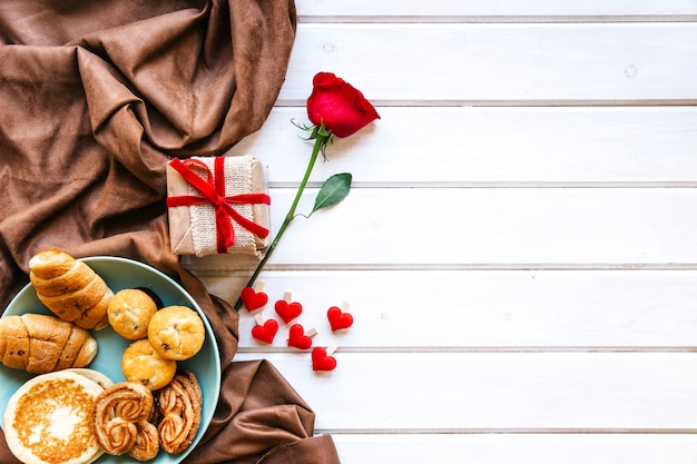 Corazones y rosa cerca de regalo y repostería