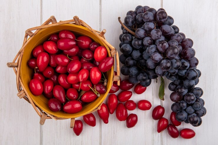 Foto gratuito cornejo vista superior en una canasta con uvas negras sobre un fondo blanco.
