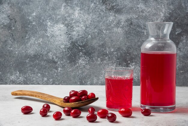 Cornelas rojas en una cuchara de madera con jugo a un lado.