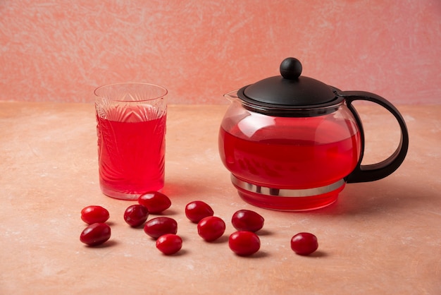 Cornelas rojas con jugo en la tetera y en el vaso.