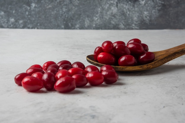 Foto gratuita cornels en una cuchara de madera sobre mesa gris.