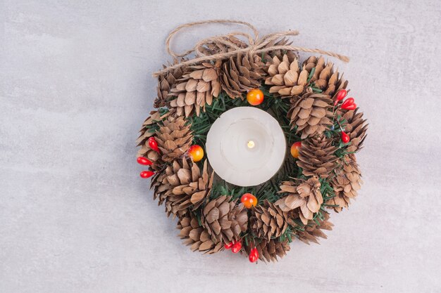 Corona de Navidad y velas en superficie blanca