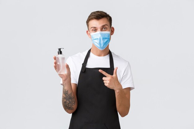 Coronavirus, distanciamiento social en cafés y restaurantes, concepto empresarial durante la pandemia. El camarero o barista explica la importancia de usar mascarilla y usar desinfectante de manos para desinfectar