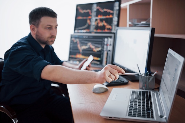 El corredor de bolsa en camisa está trabajando en una sala de monitoreo con pantallas. Concepto gráfico de la bolsa de comercio de Forex Finance. Empresarios que negocian acciones en línea