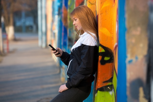 Corredor chica descansando con teléfono móvil en la calle
