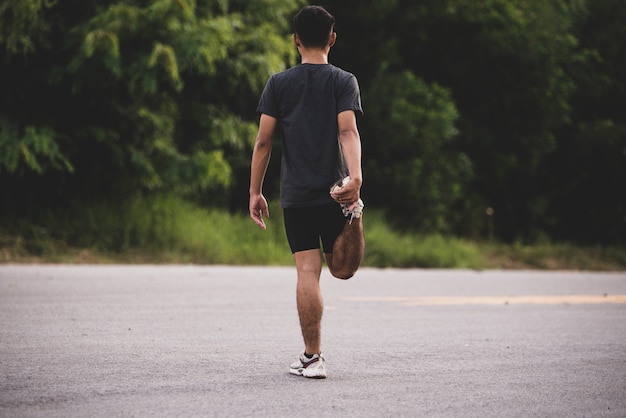 Corredor masculino haciendo ejercicios de estiramiento, preparándose para el entrenamiento