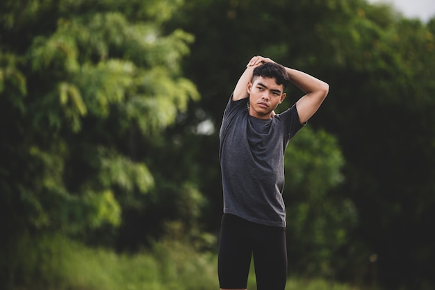 Corredor masculino haciendo ejercicios de estiramiento, preparándose para el entrenamiento