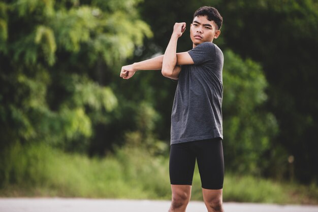 Corredor masculino haciendo ejercicios de estiramiento, preparándose para el entrenamiento